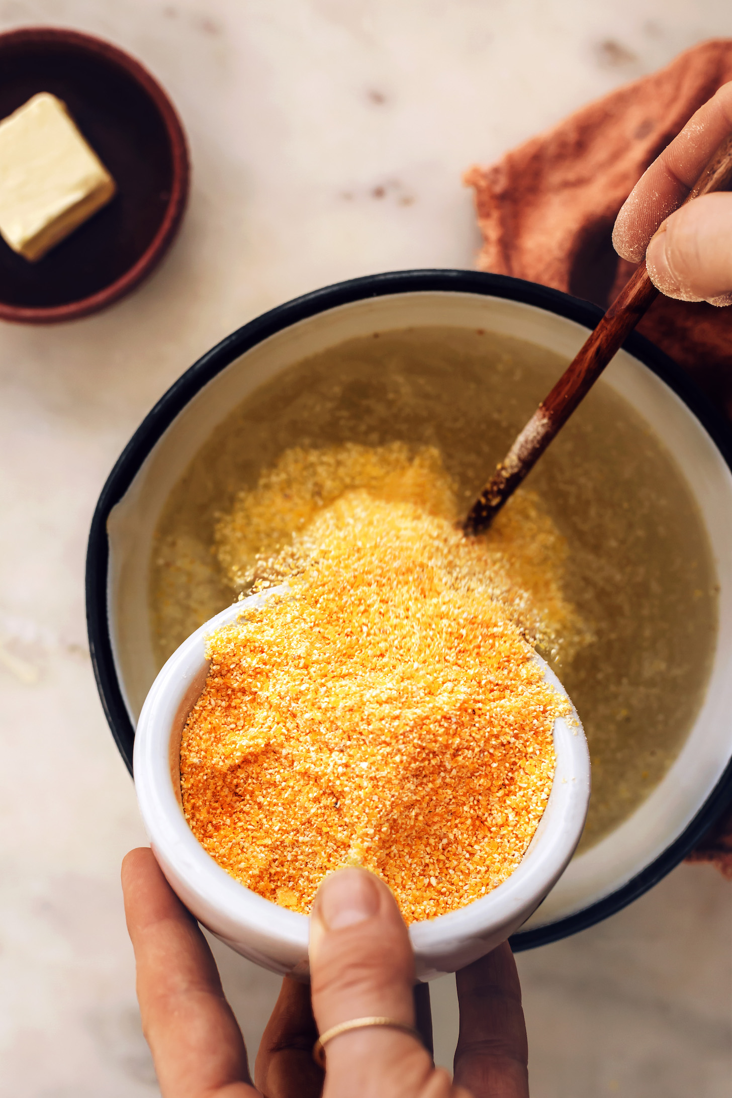 Pouring corn grits into a pot of water