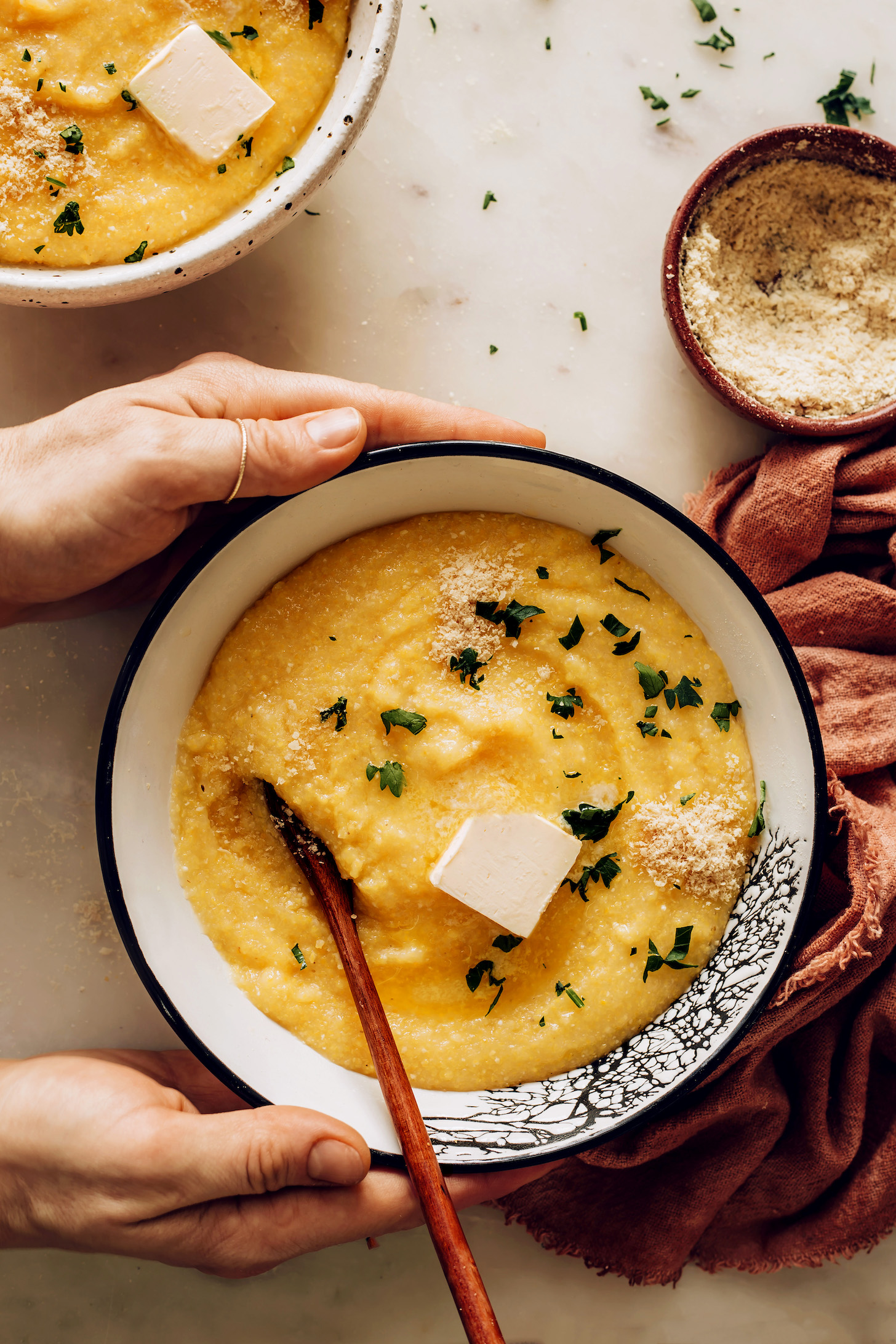 Bowl of vegan polenta with fresh herbs and vegan parmesan