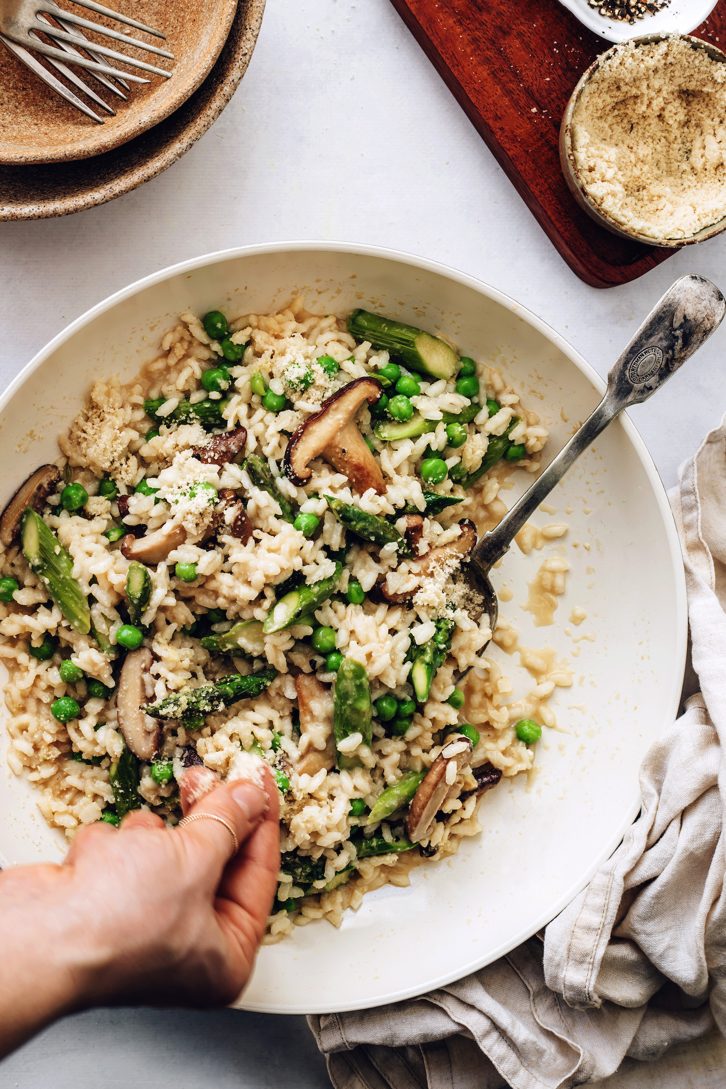 Sprinkling vegan parmesan cheese over risotto