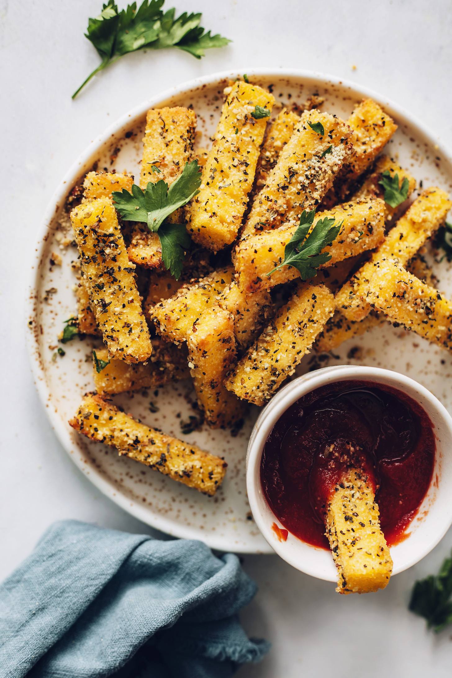 Plate of polenta fries seasoned with Italian herbs and vegan parmesan