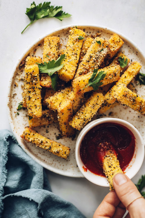 Dipping a polenta fry into a bowl of marinara sauce