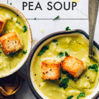 Two bowls of creamy green split pea soup topped with homemade croutons