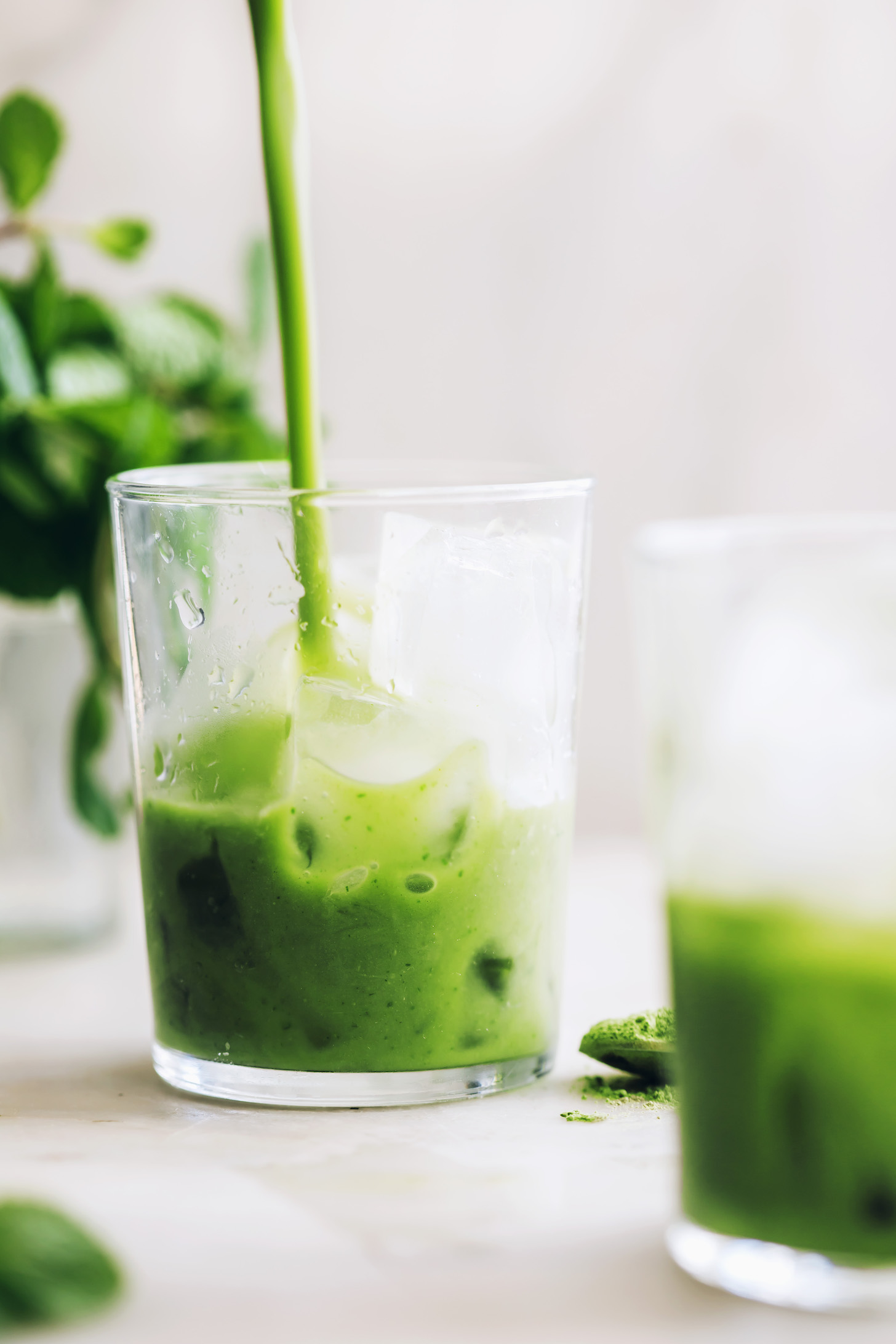 Pouring a mint matcha latte over ice