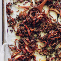 Wooden spoon scooping up roasted cabbage on a baking sheet