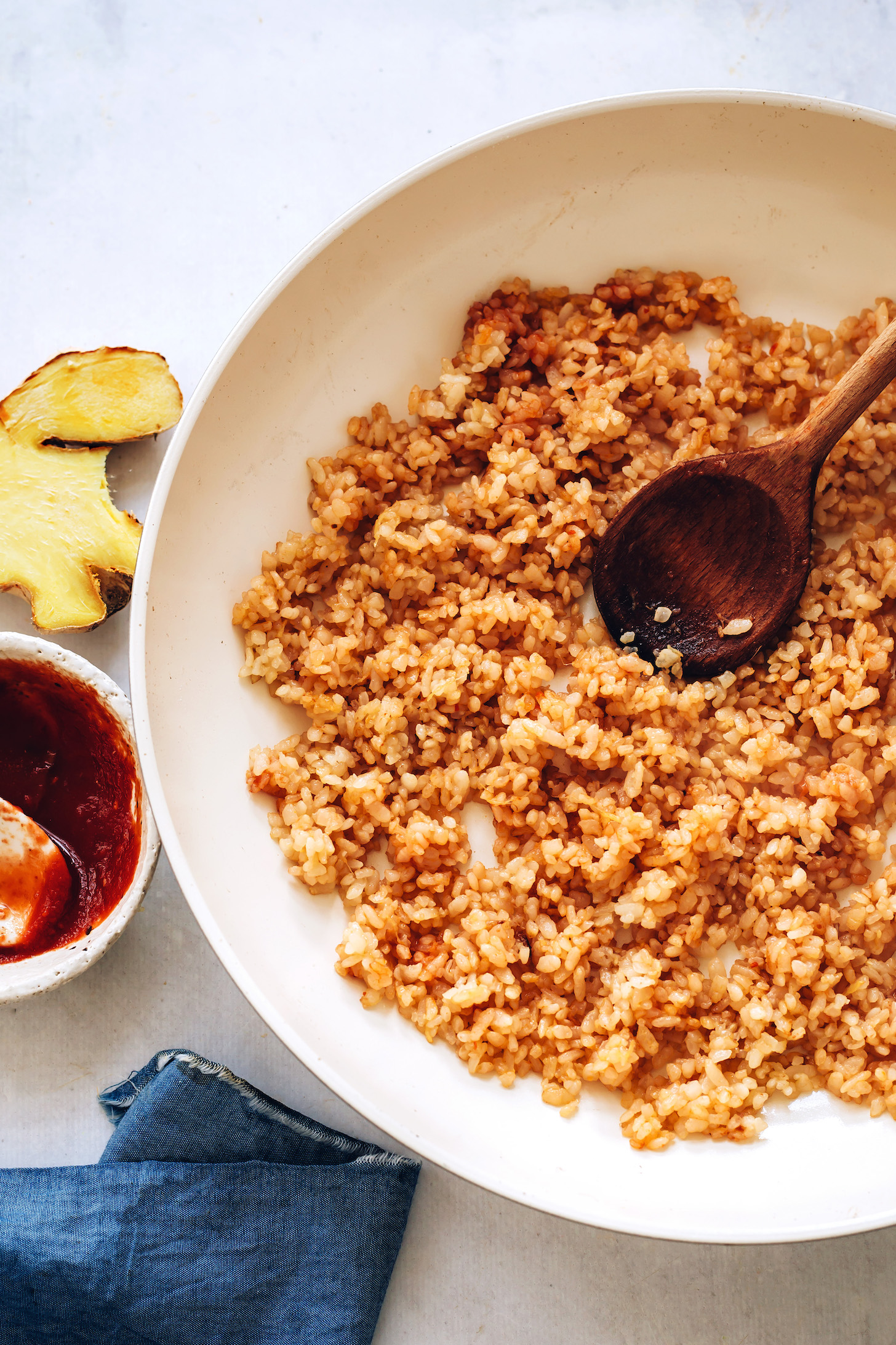 Pan of cooked brown rice next to ginger and gochujang sauce