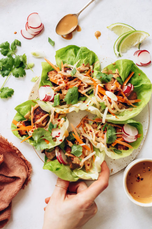 Picking up a tofu lettuce wrap from a platter