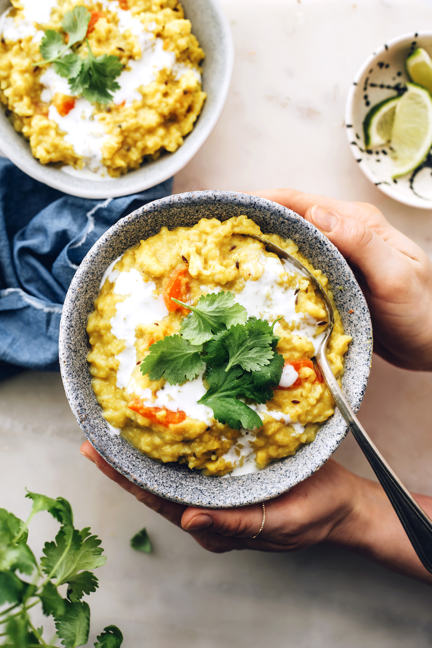 Holding a bowl of kitchari topped with cilantro and coconut milk