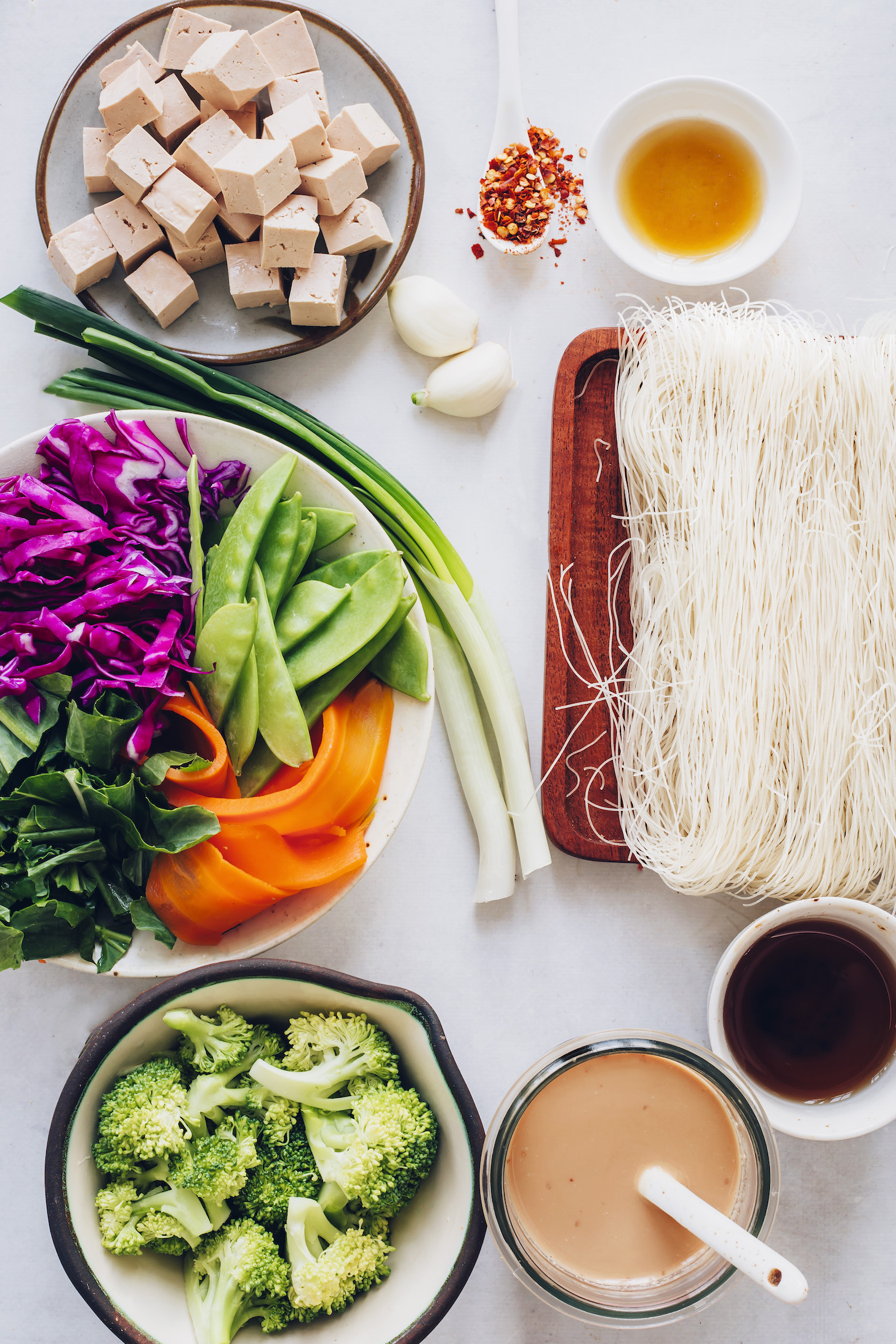 Tofu, green onions, vegetables, stir fry sauce, garlic, rice noodles, chili flakes, sesame oil, and tamari