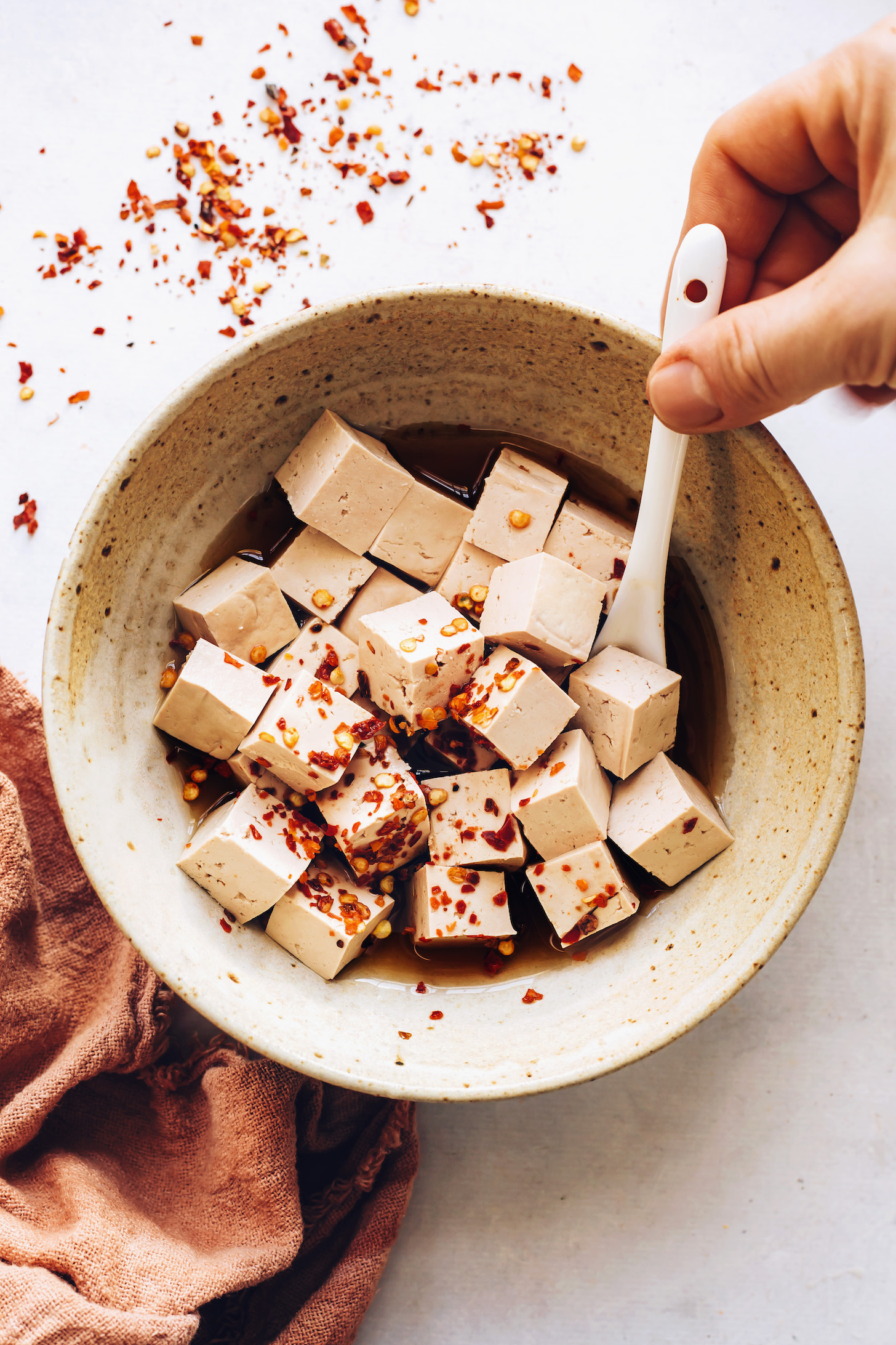 Marinating cubed tofu in tamari, toasted sesame oil, and red pepper flakes