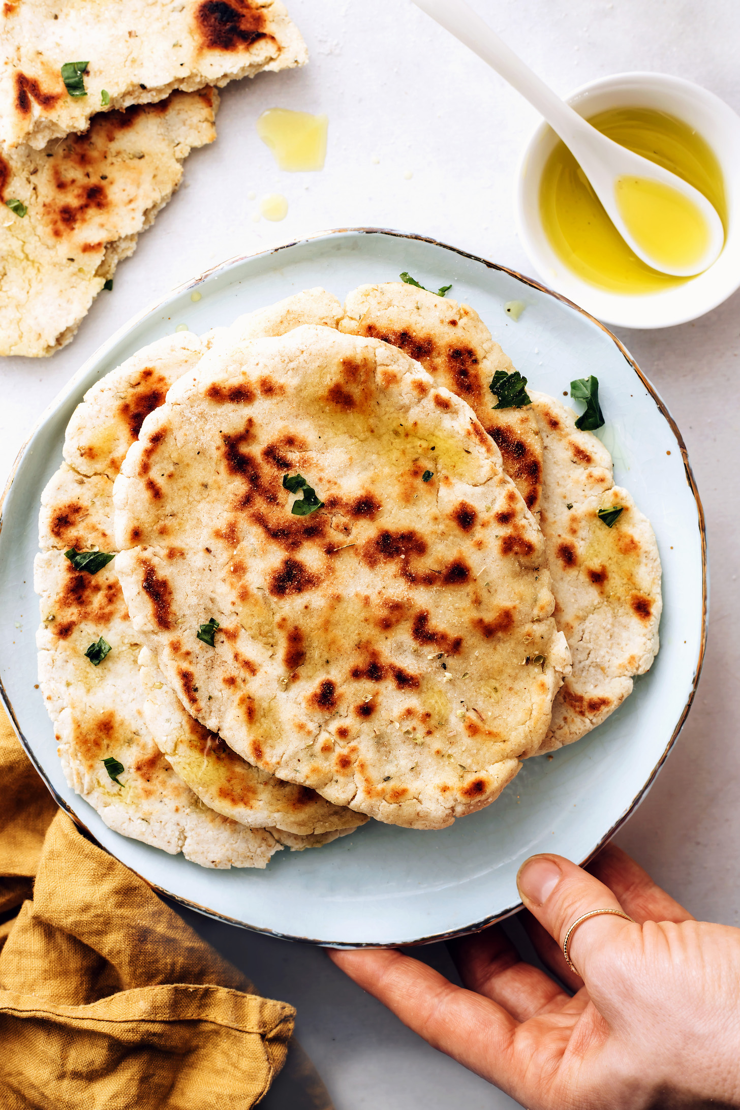 Bowl of olive oil next to a plate stacked with gluten-free flatbread