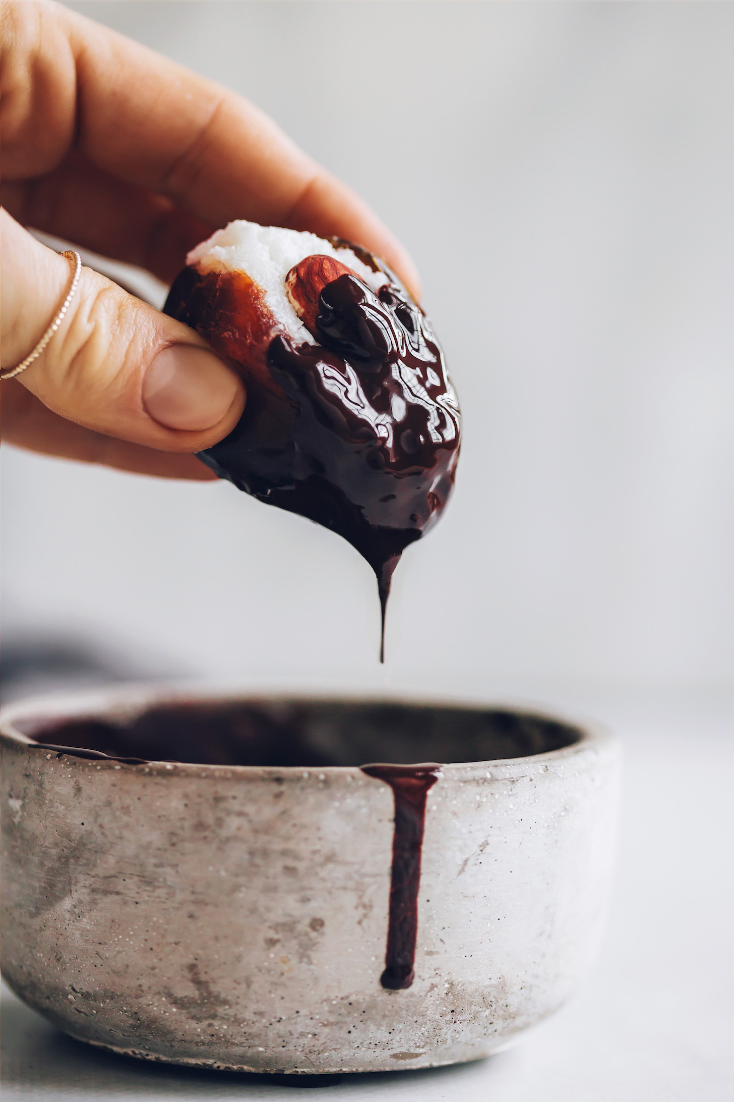 Dipping a stuffed date into melted chocolate
