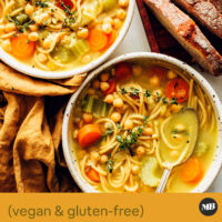 Bowls of vegan chickpea noodle soup with slices of bread
