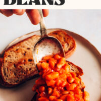 Scooping baked beans on a slice of toast with text above it saying Easy Baked Beans served on toast