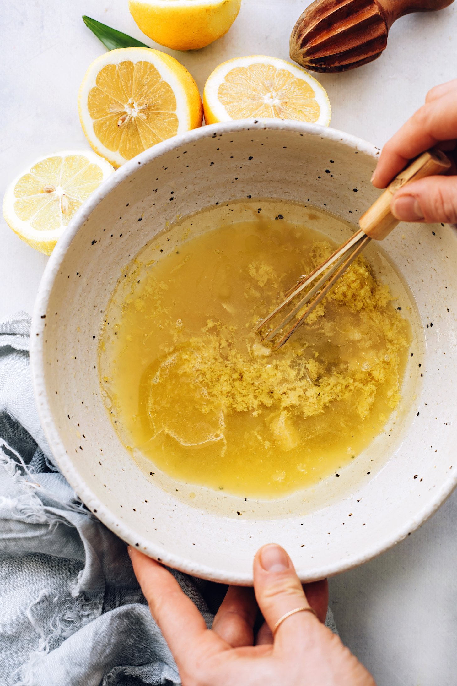 Whisking lemon juice, lemon zest, applesauce, and avocado oil in a bowl