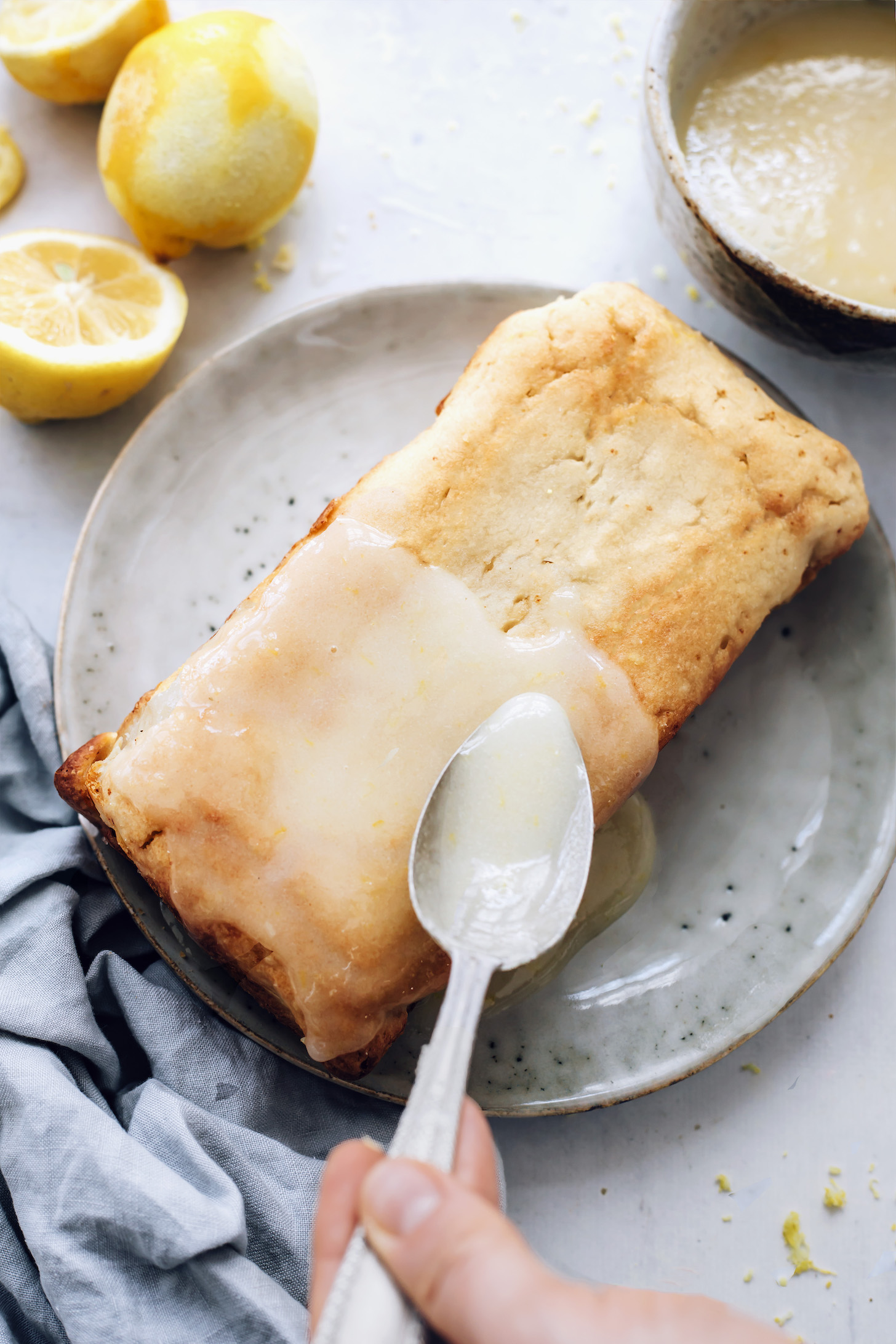 Drizzling lemon glaze over our lemon loaf cake