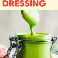 Green goddess dressing sliding off a spoon into a jar