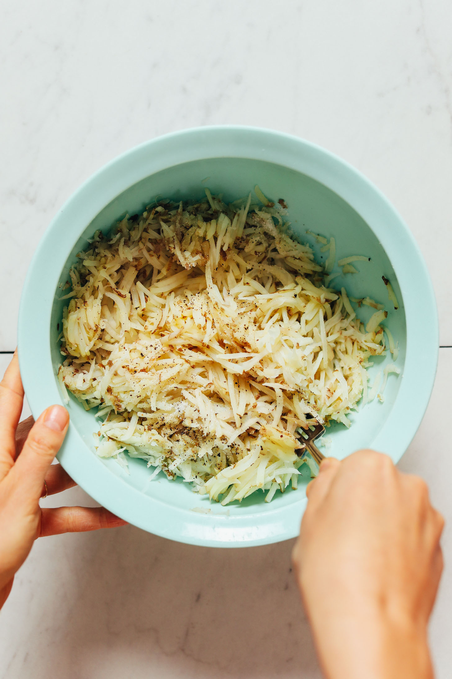 Stirring grated potatoes with salt and pepper