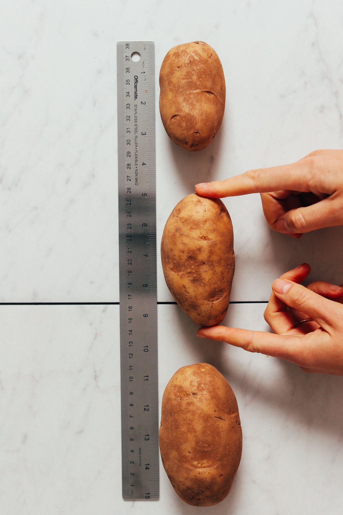 Small, medium, and large potatoes next to a ruler for showing scale