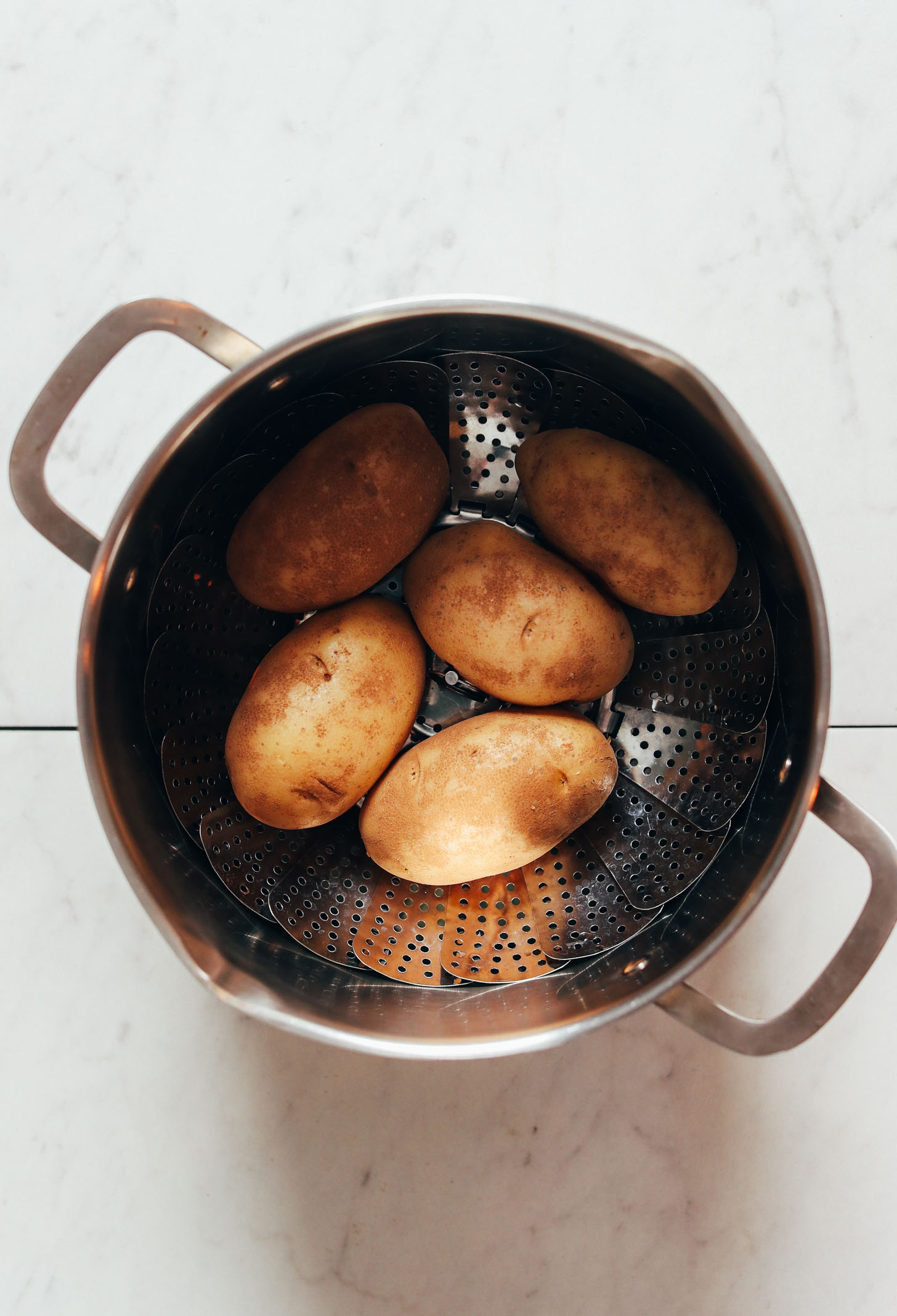 Russet potatoes in a steamer basket