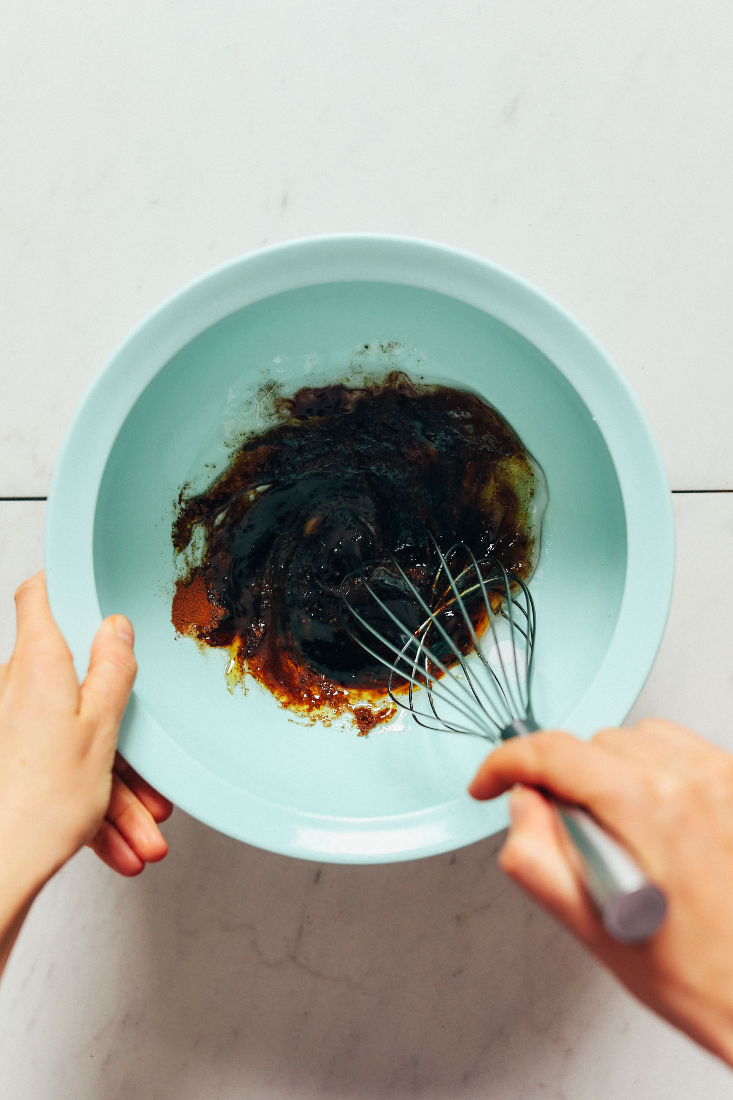 Whisking coconut sugar, baking soda, sea salt, cinnamon, maple syrup, molasses, and melted coconut oil