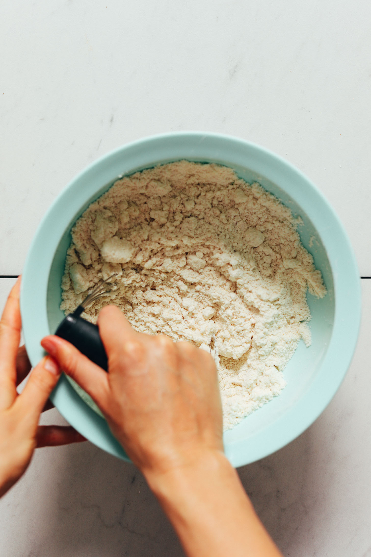 Using a pastry cutter to cut coconut oil into dry ingredients