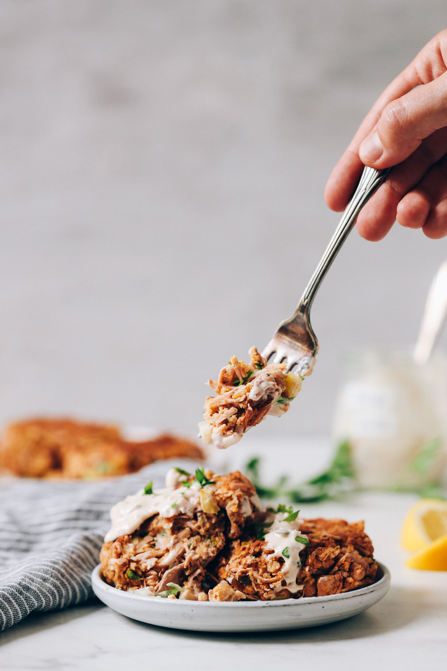 Picking up a bite of a vegan crab cake from a plate