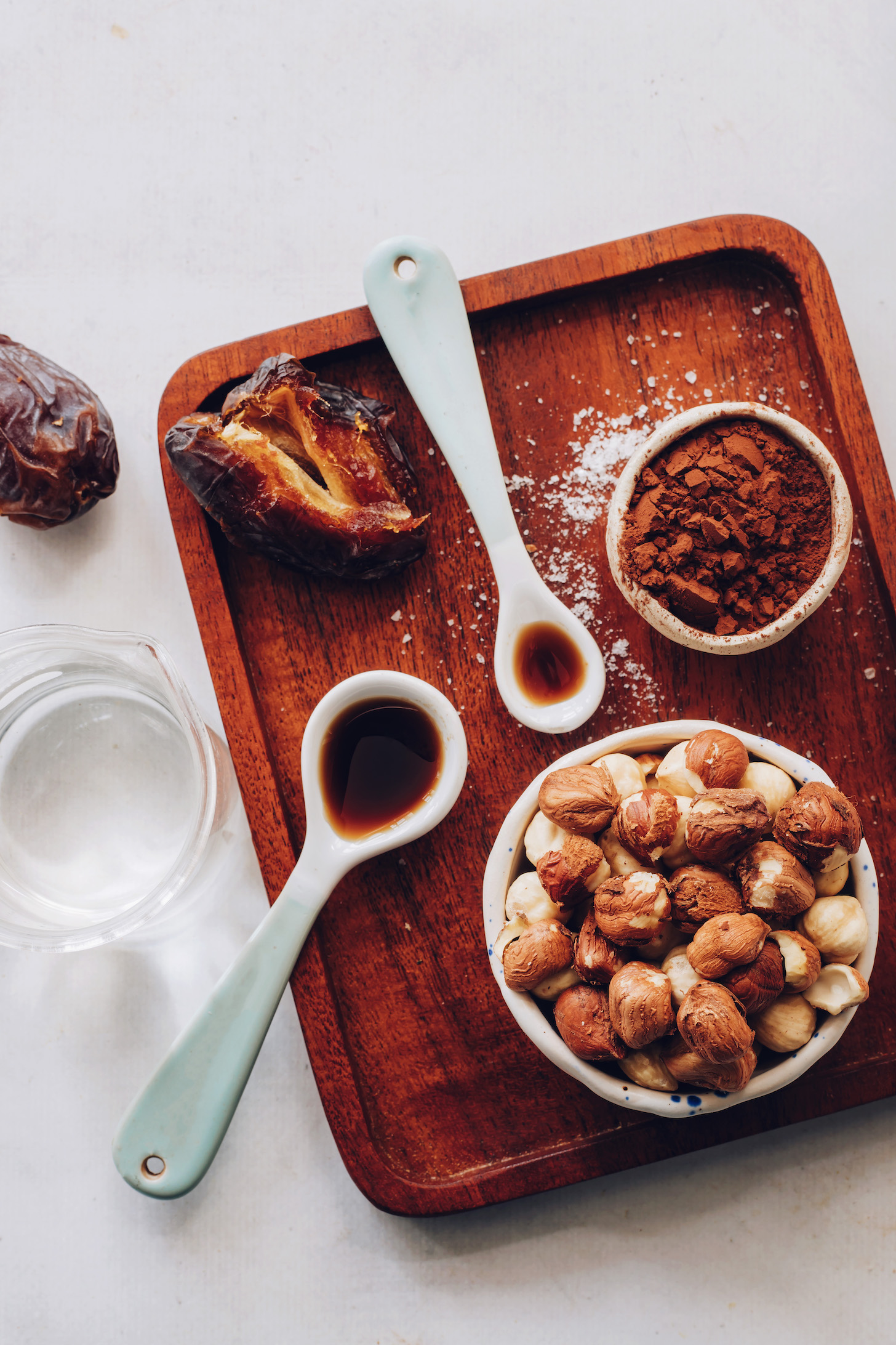 Wood tray with dates, cocoa powder, hazelnuts, vanilla, maple syrup, and water