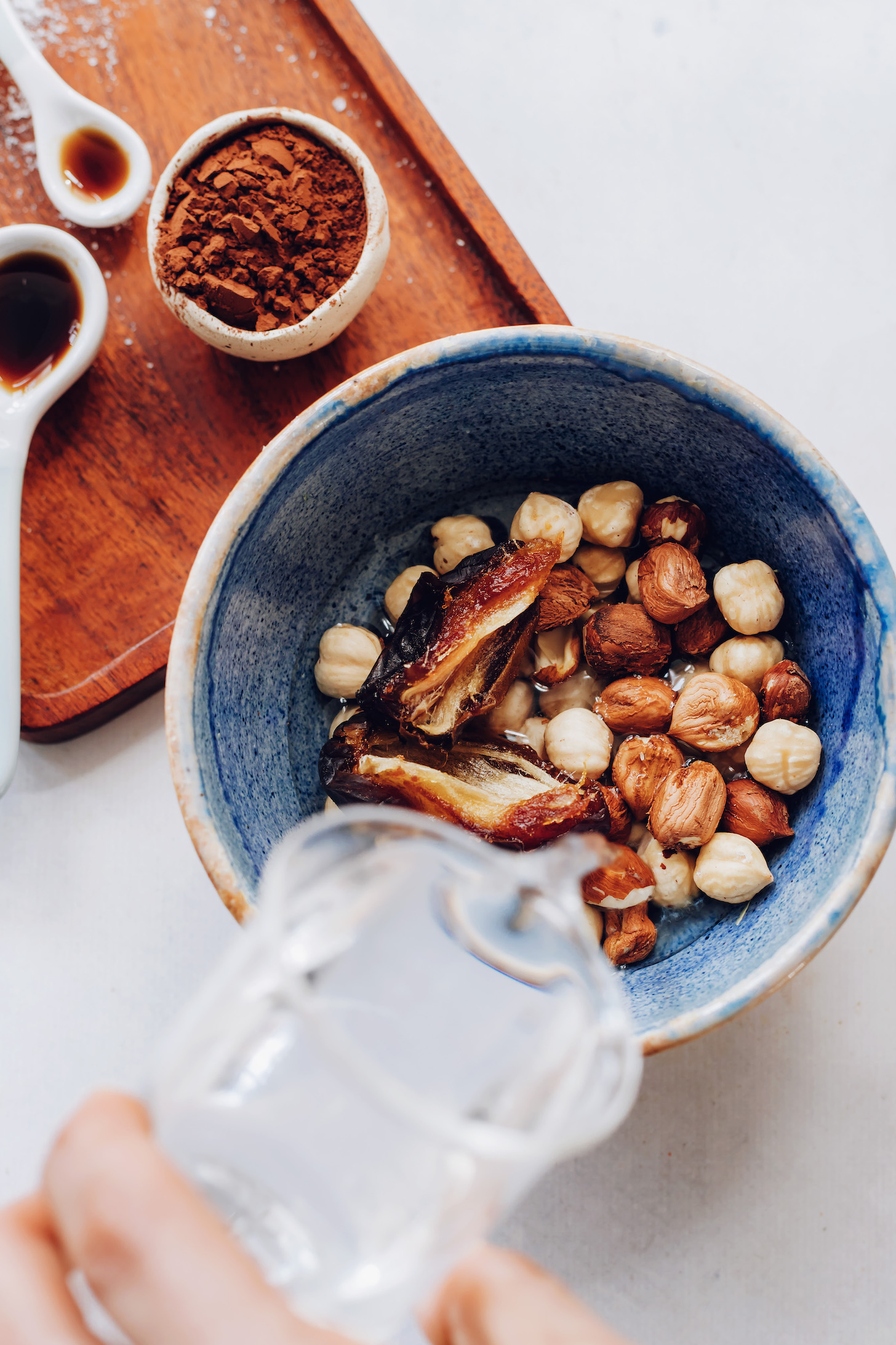 Pouring water over a bowl of hazelnuts and dates