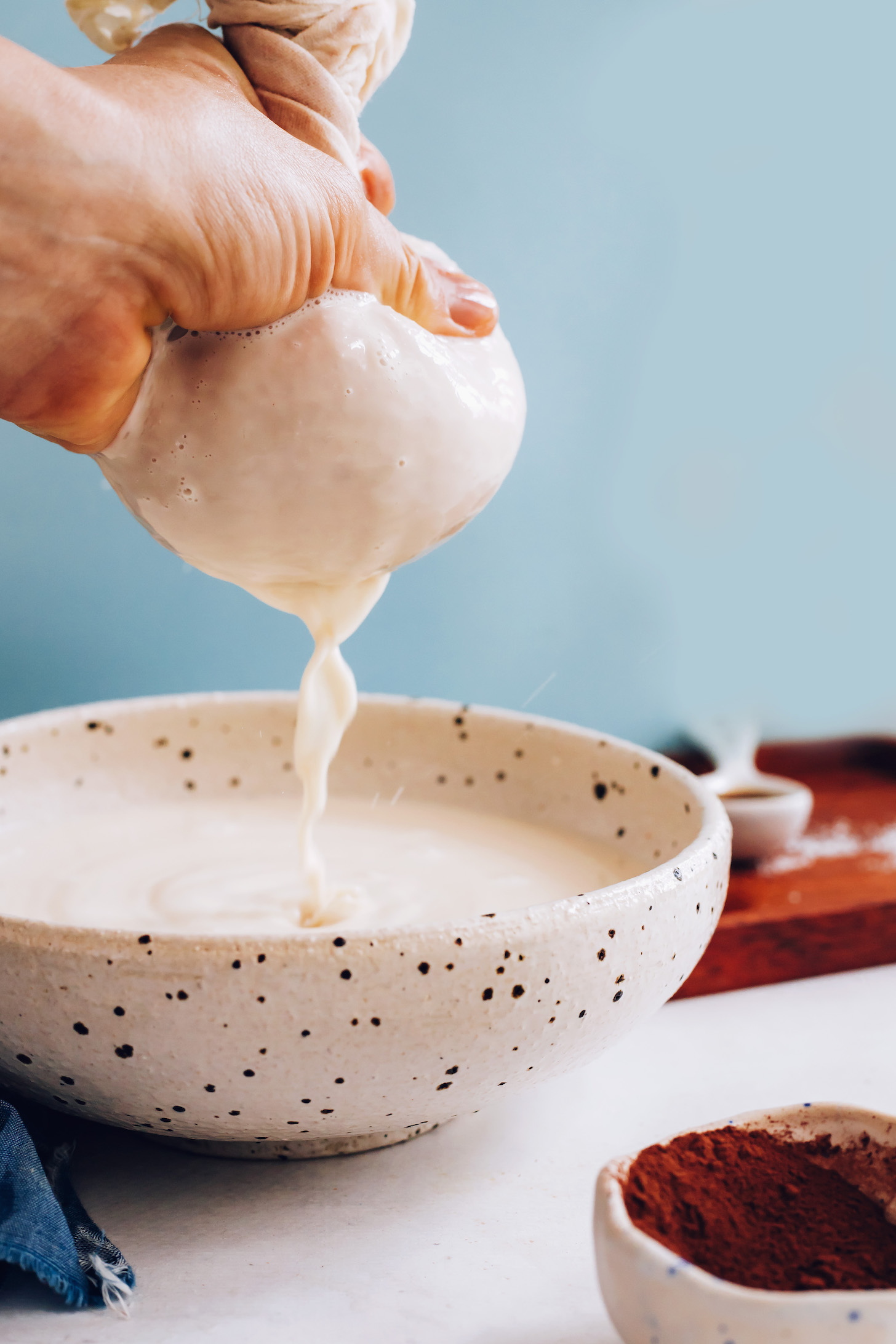 Squeezing hazelnut milk through a nut milk bag into a bowl