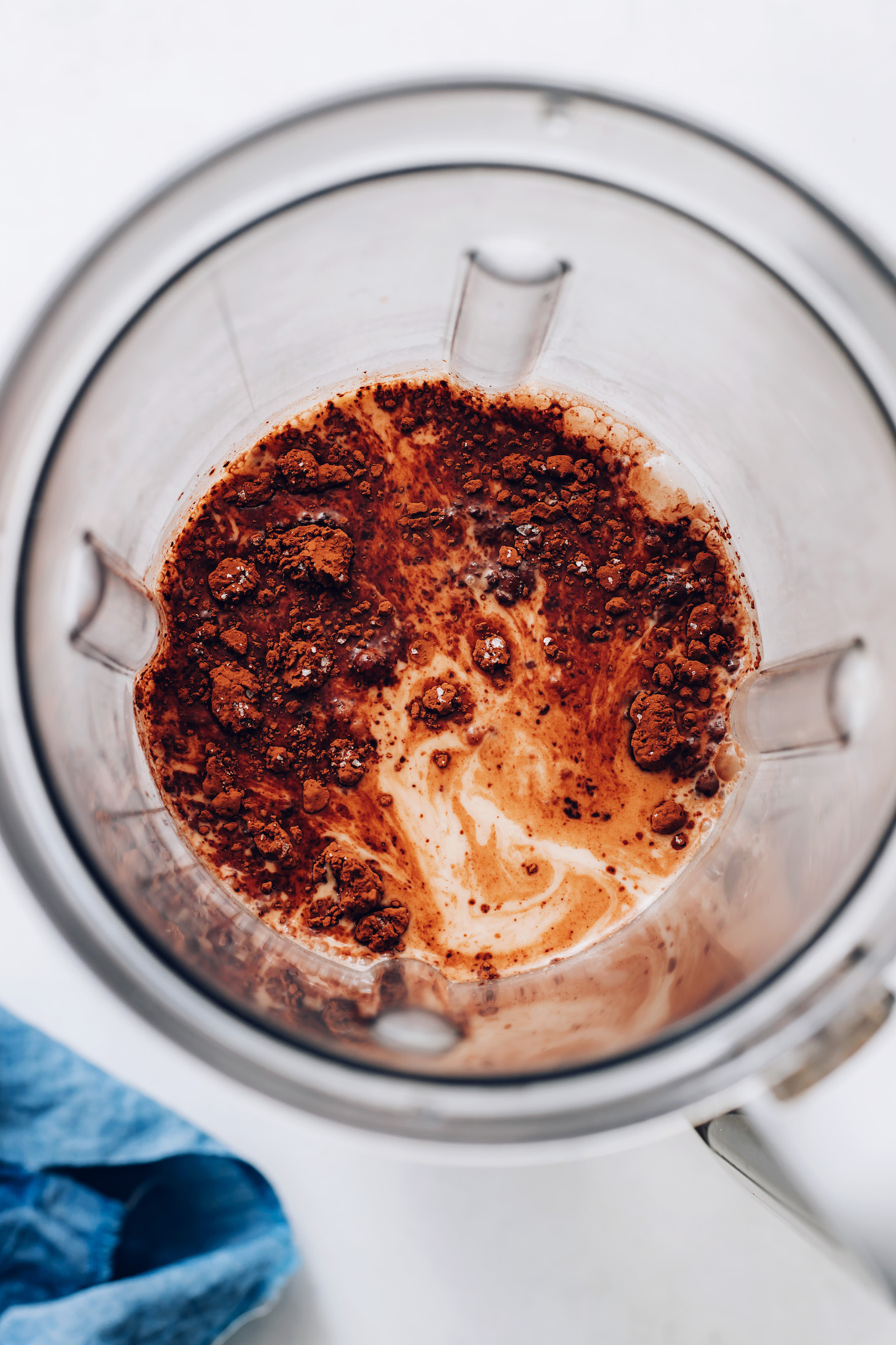 Blender with cocoa powder over creamy hazelnut milk