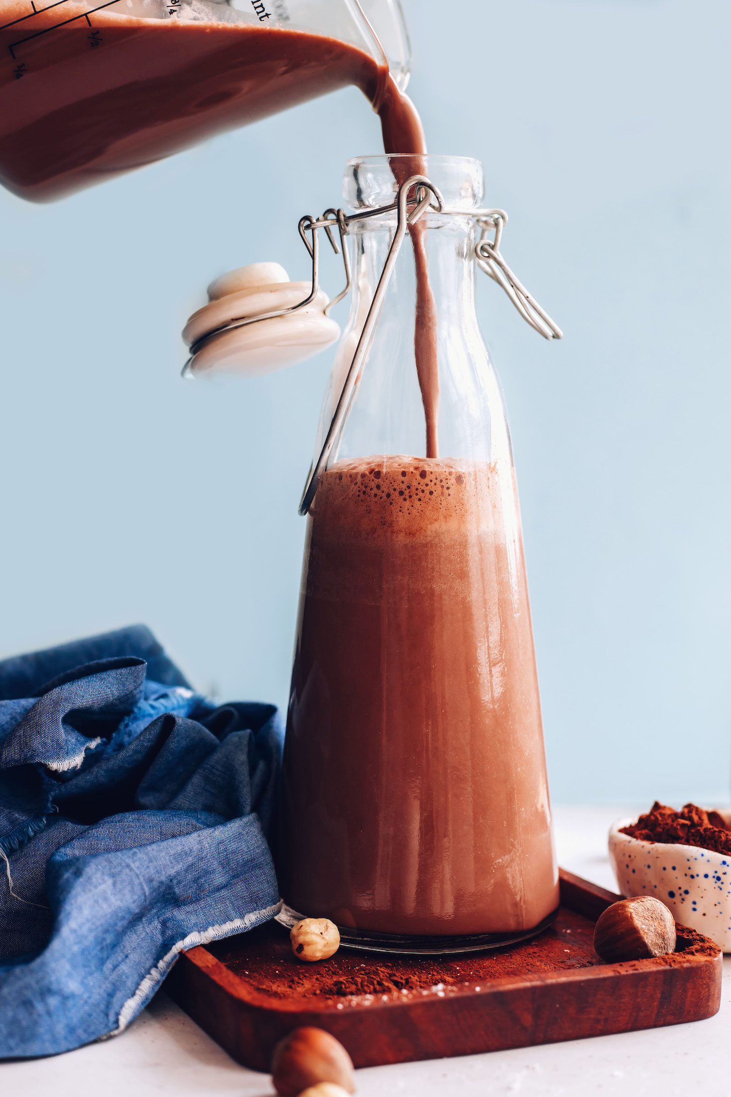 Pouring homemade chocolate hazelnut milk into a glass jug
