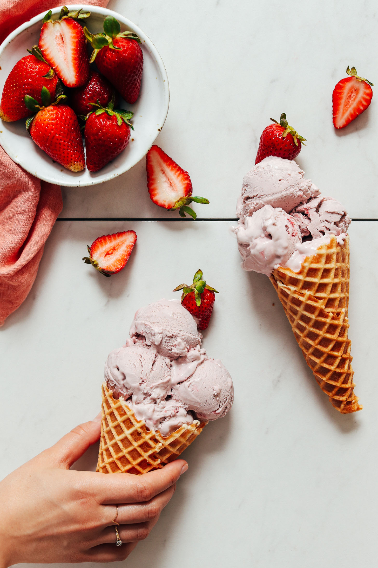 Holding a waffle cone of vegan strawberry ice cream