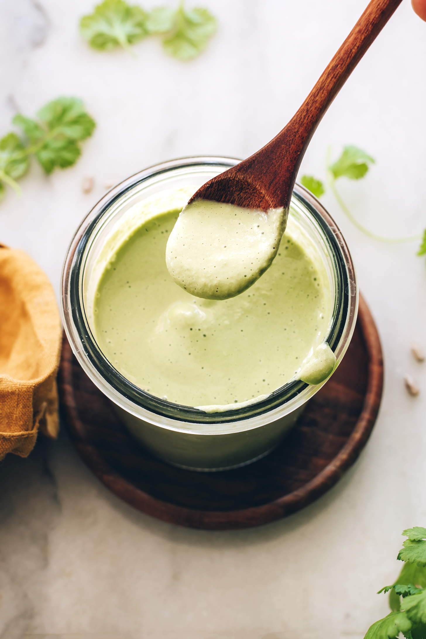 Holding a spoonful of cilantro sunflower seed dressing over a jar