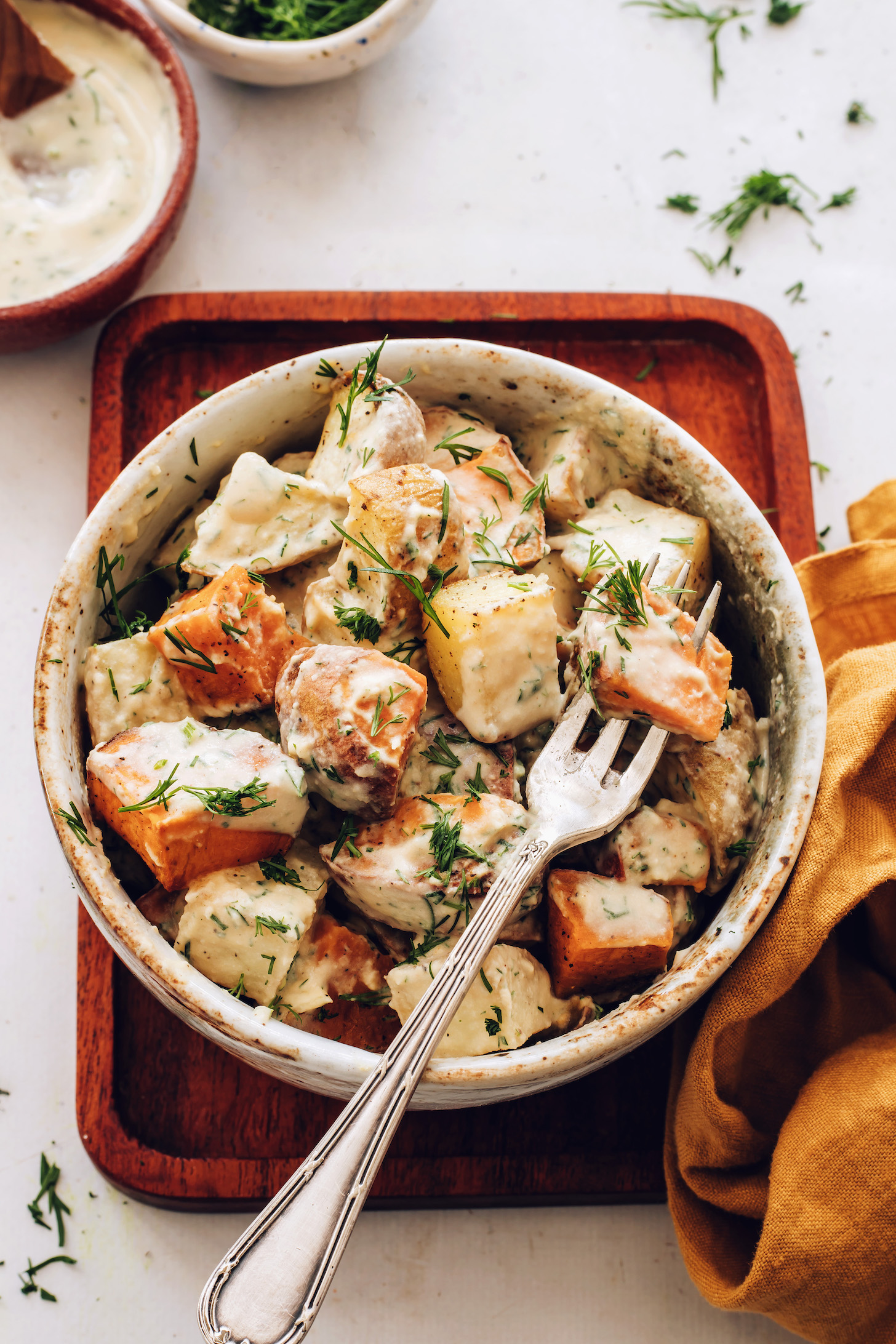 Fork in a bowl of roasted potato salad sprinkled with fresh dill