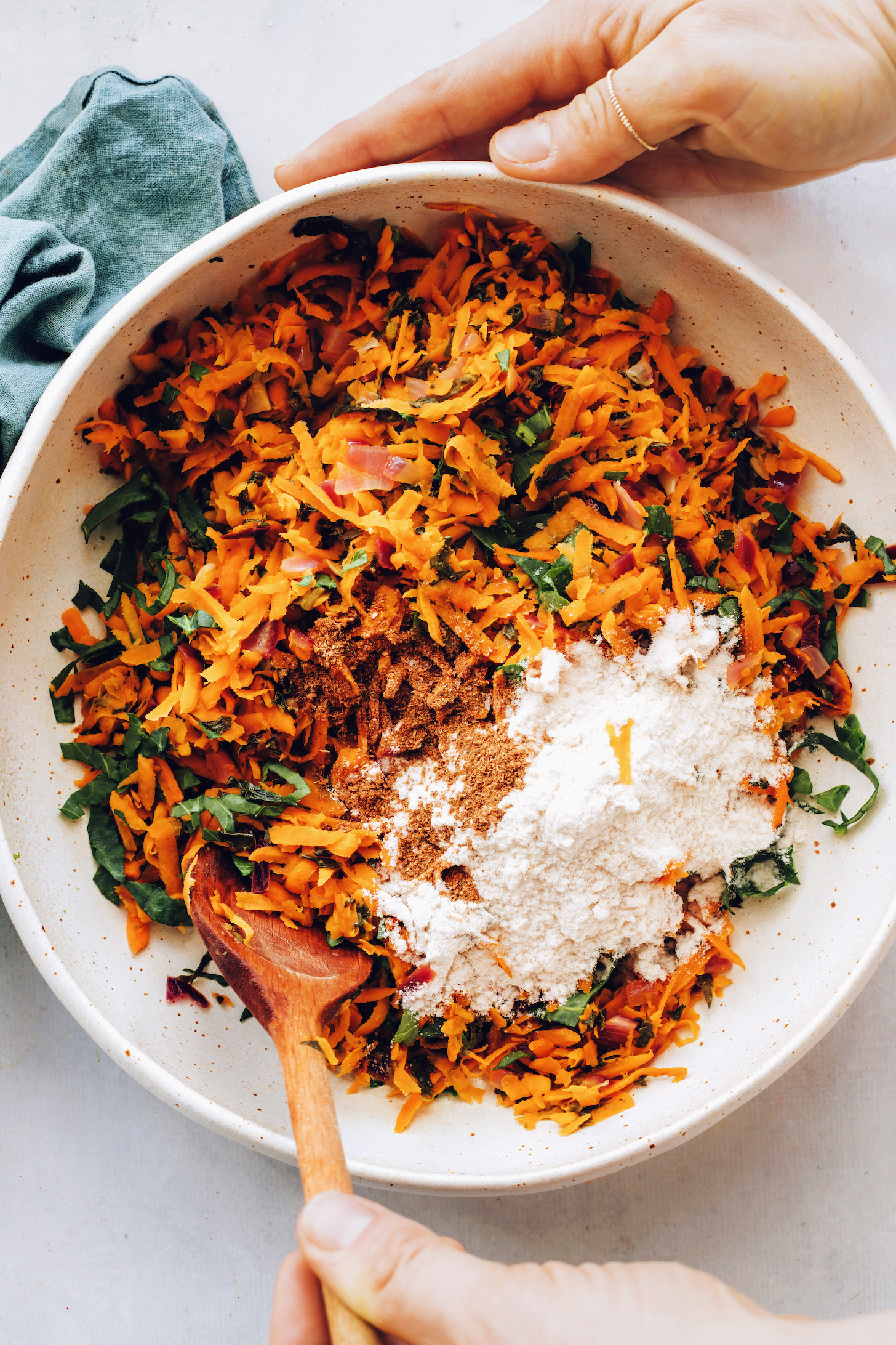 Bowl with shredded sweet potato, kale, red onion, salt, garam masala, and rice flour