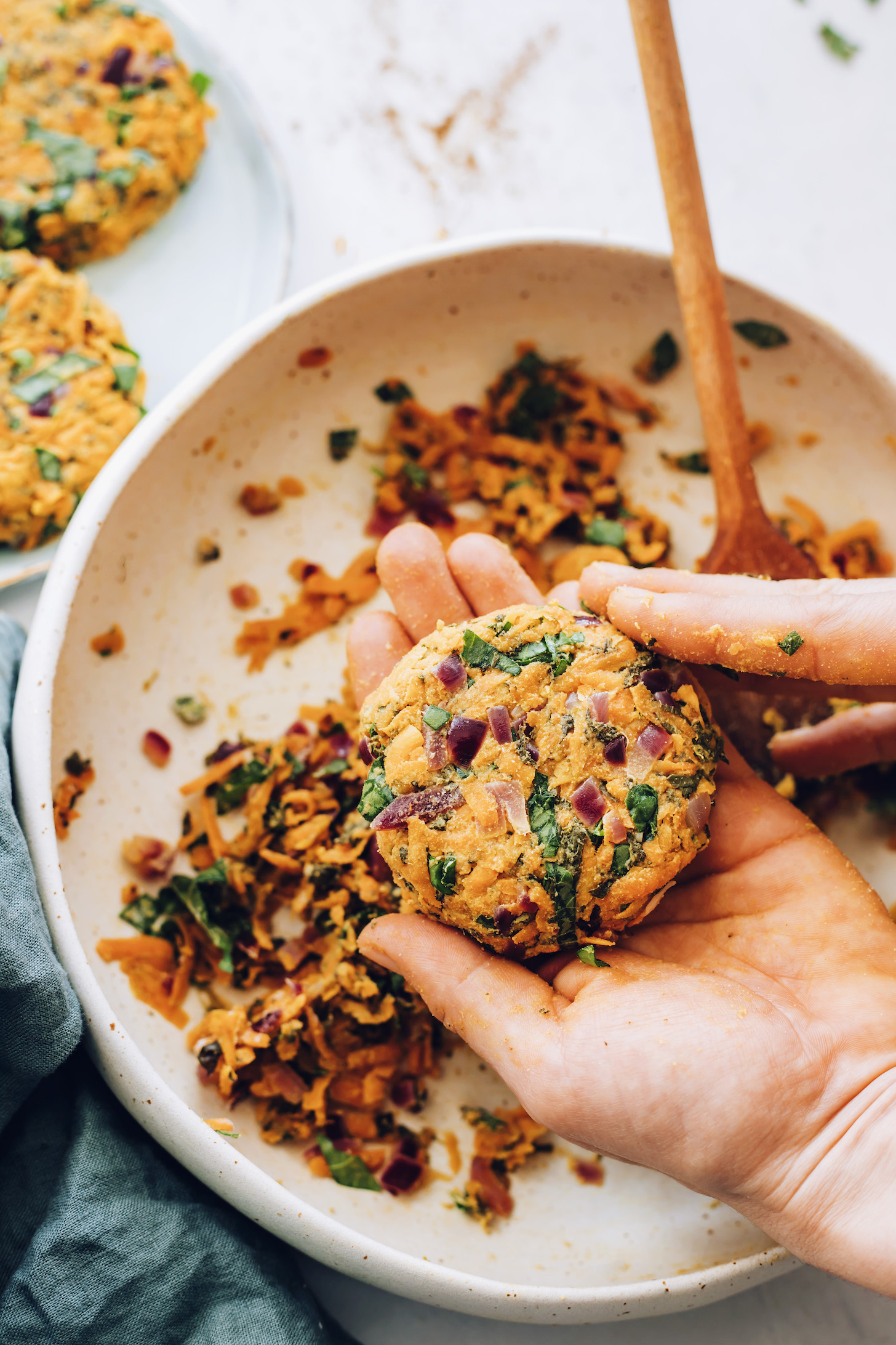 Forming a sweet potato fritter over a mixing bowl