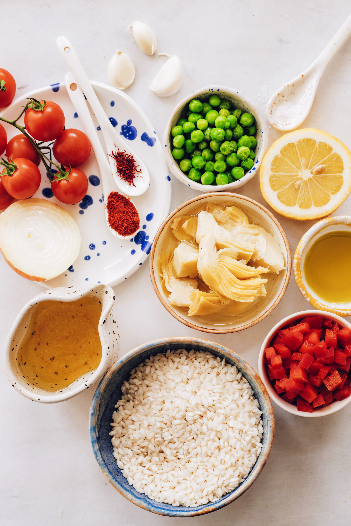 Cherry tomatoes, onion, smoked paprika, saffron, green peas, lemon, artichoke hearts, olive oil, red bell pepper, arborio rice, and vegetable broth