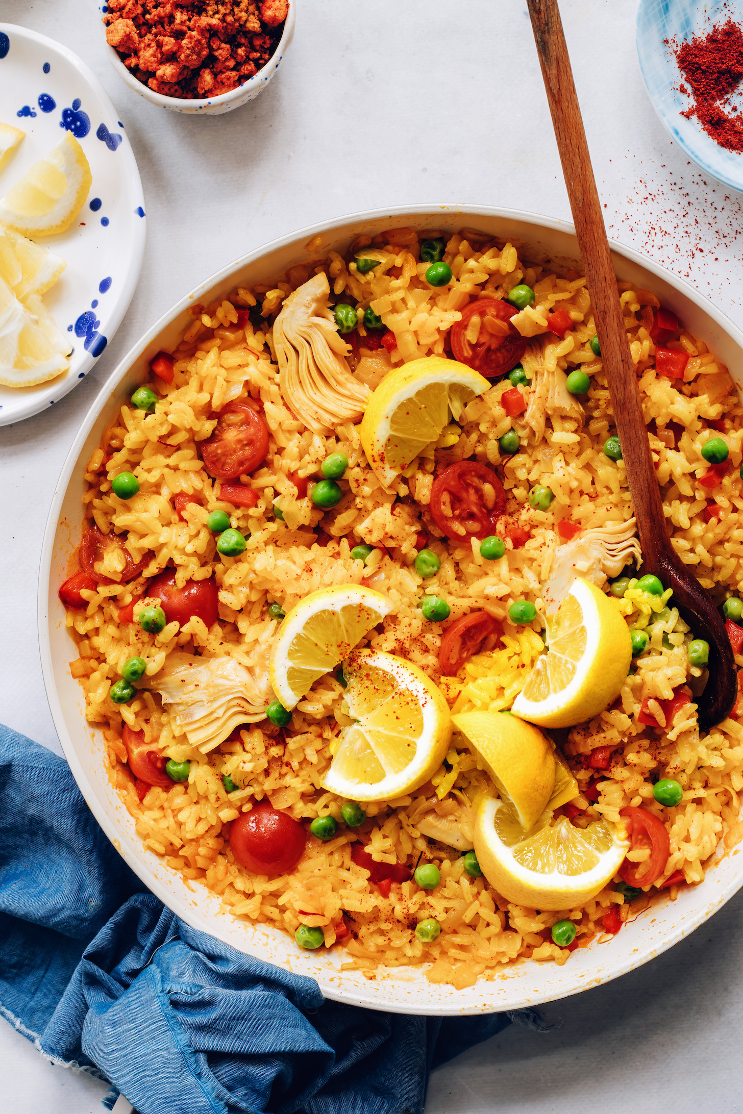 Pan of vegan paella topped with lemon wedges