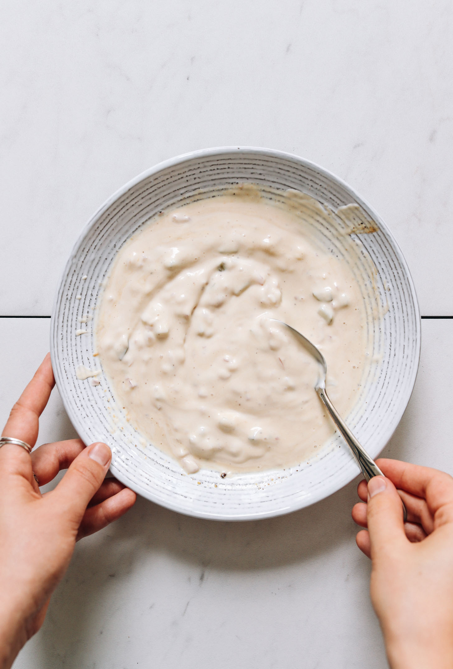 Stirring vegan tartar sauce in a bowl
