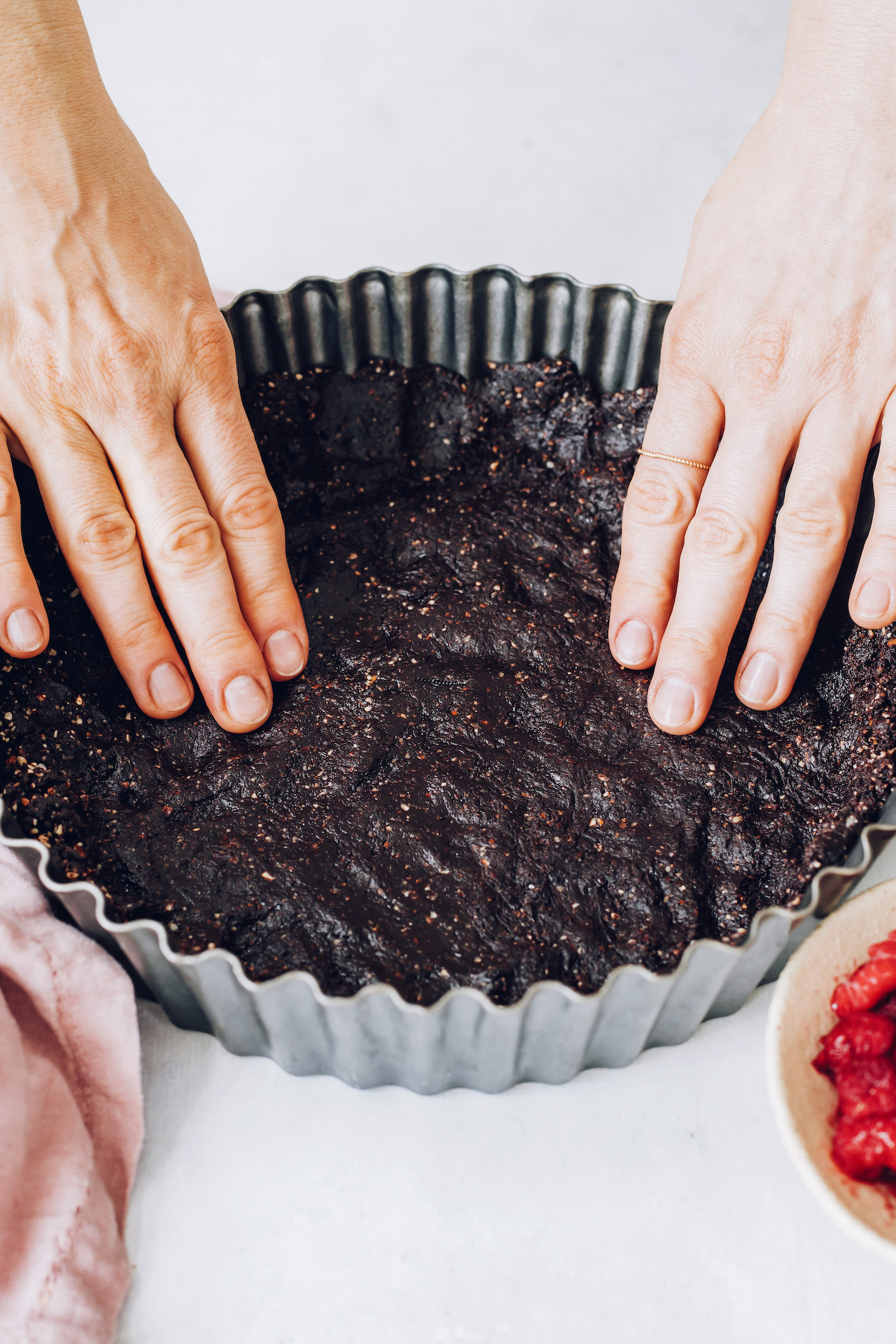 Pressing the dark chocolate date crust into a tart pan