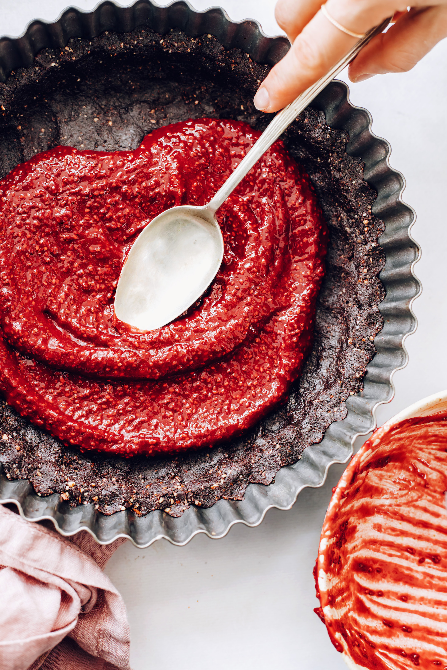 Spreading the raspberry filling over the chocolate date crust