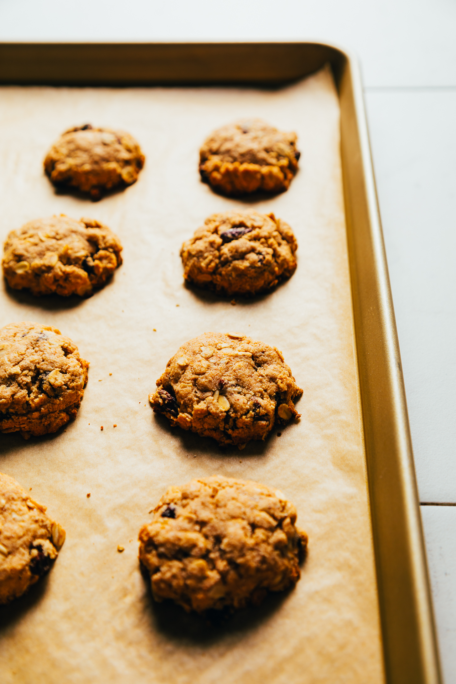 Parchment-lined baking sheet of vegan oatmeal raisin cookies