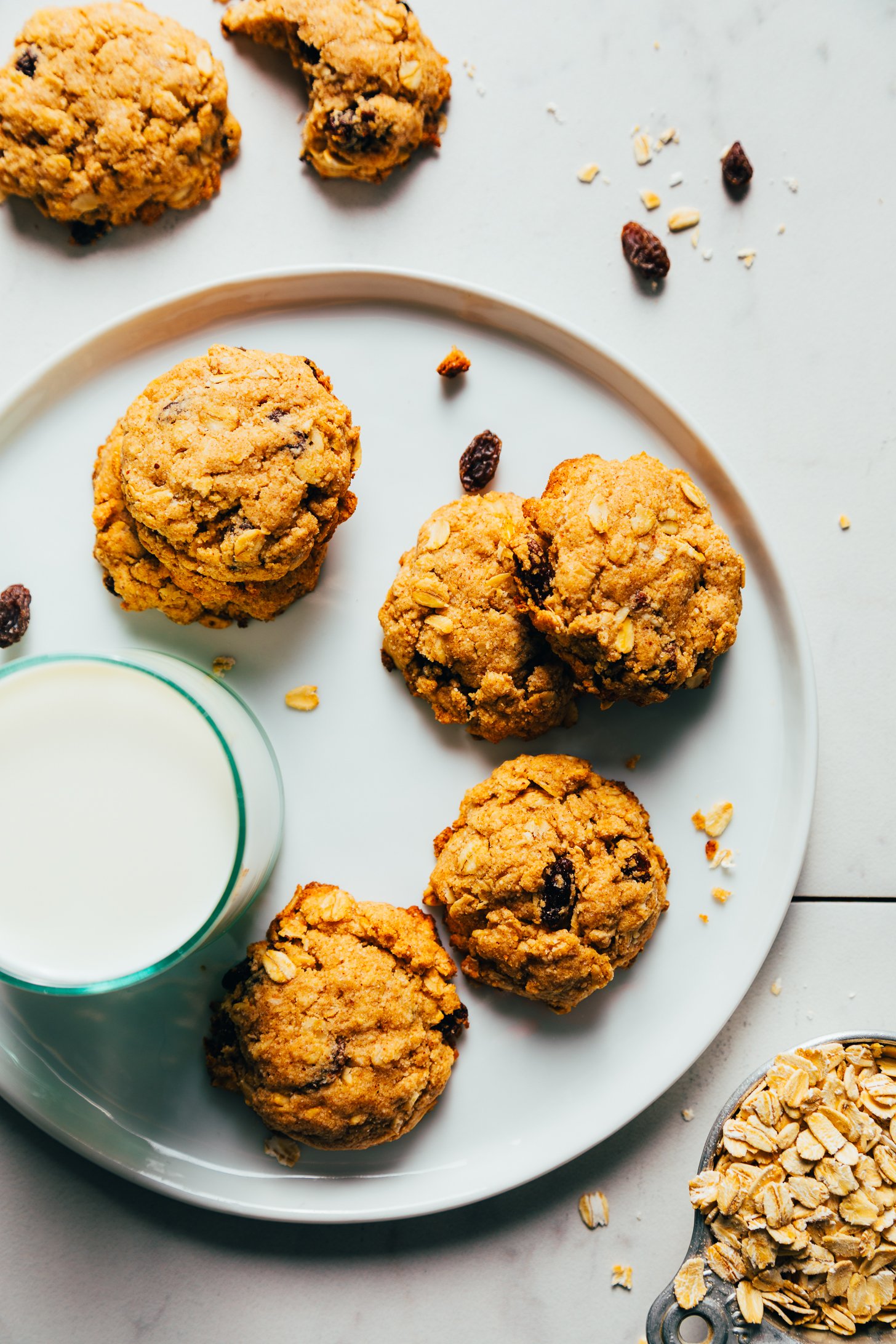 Glass of almond milk on a plate of vegan oatmeal raisin cookies