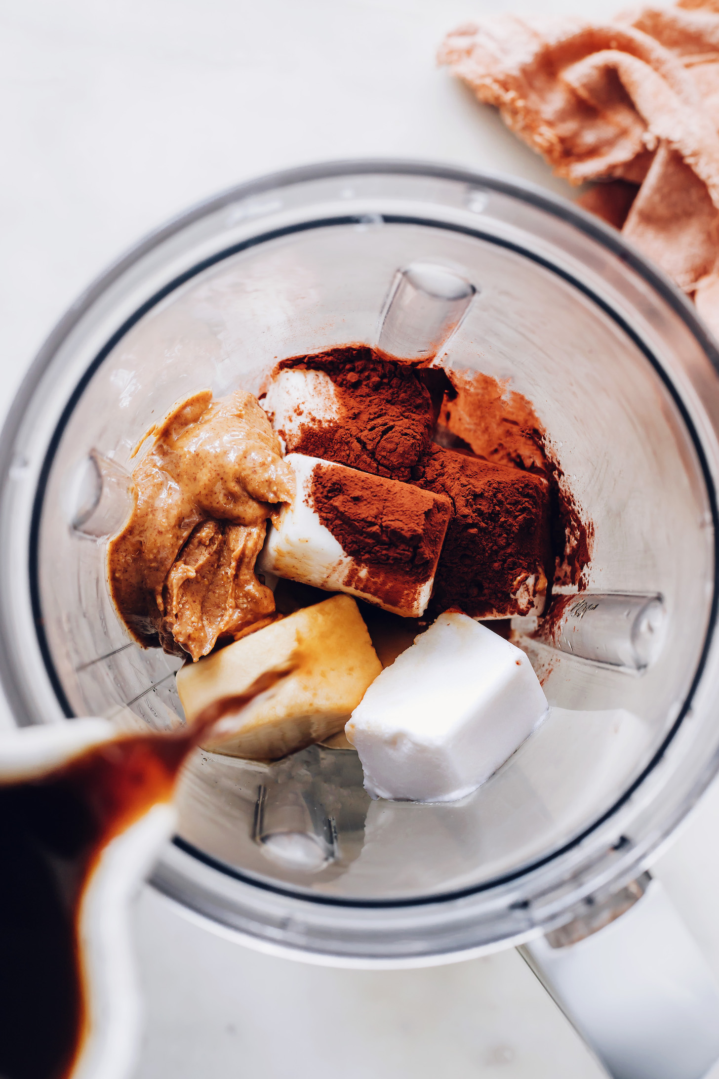 Pouring coffee over coconut milk ice cubes in a blender