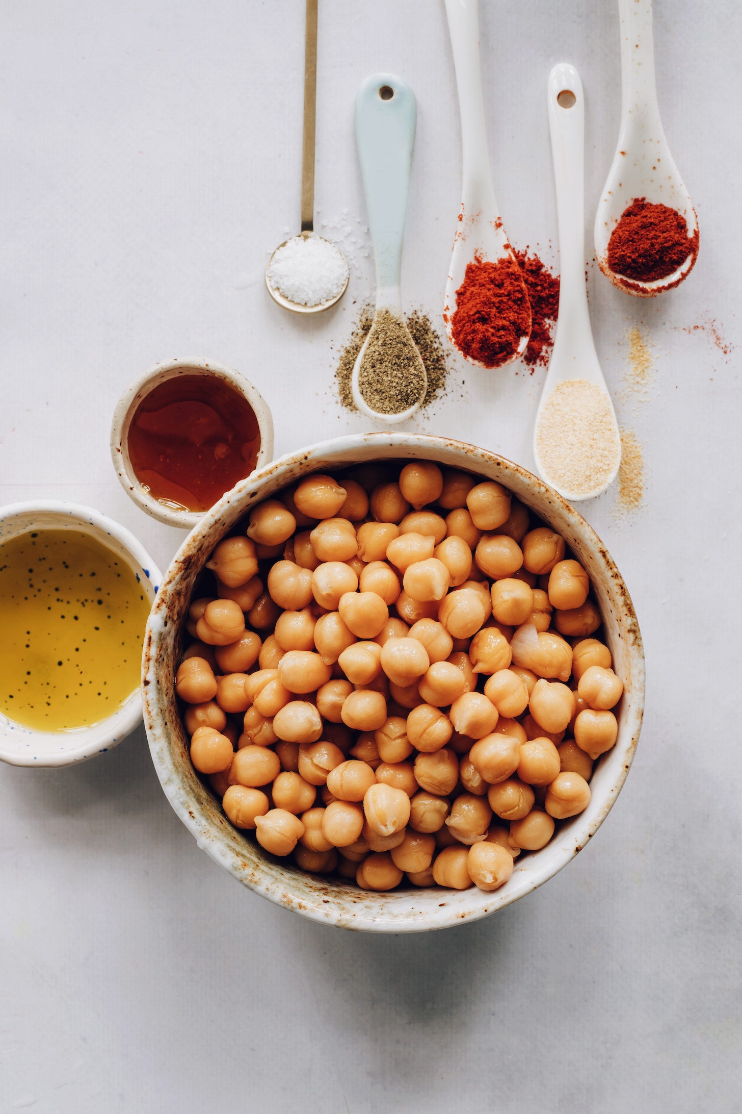 Bowl of chickpeas next to avocado oil, maple syrup, and spices