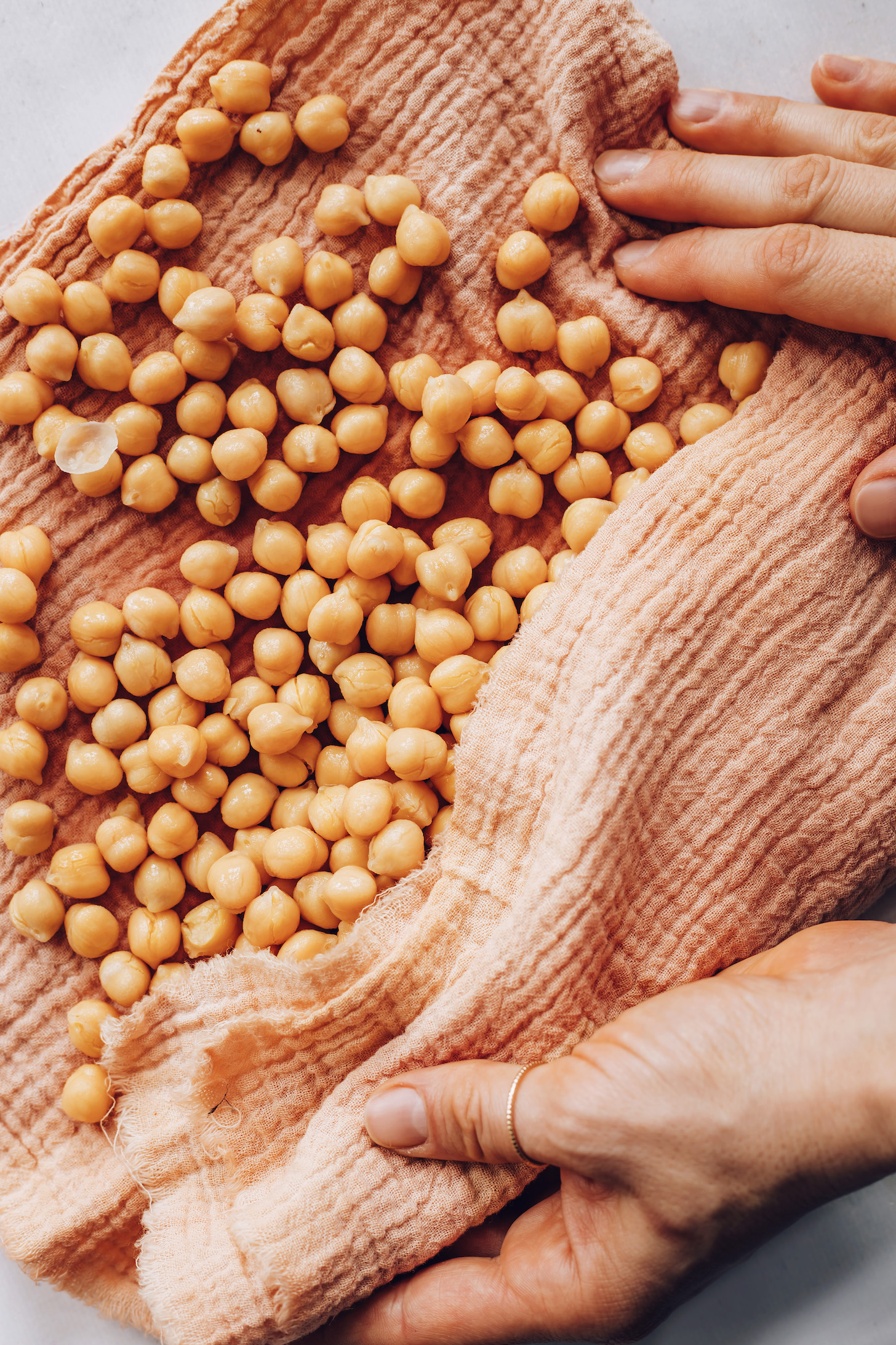Using a kitchen towel to remove the peels from garbanzo beans