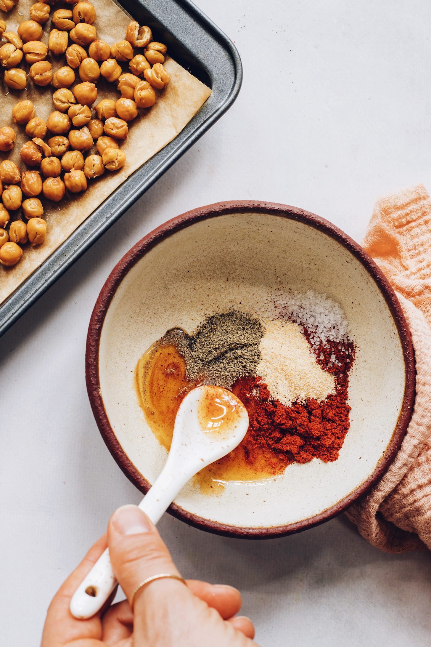 Baking sheet of roasted chickpeas and a bowl of spices and maple syrup