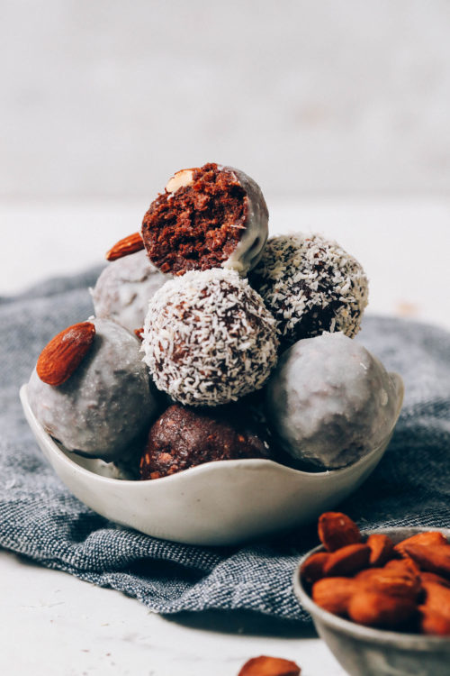 Bowl of Almond Joy Energy Bites and measuring cup of raw almonds