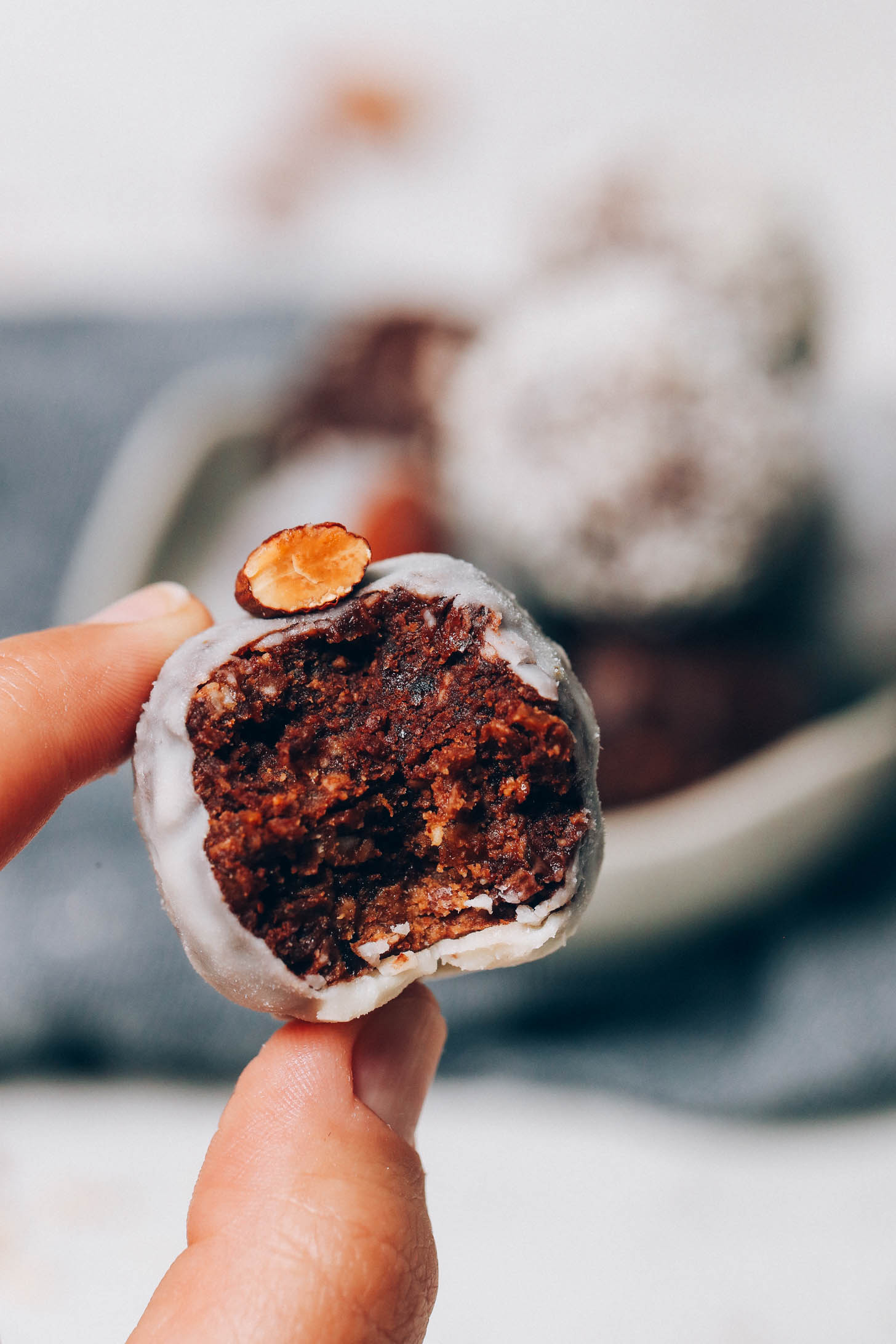 Holding up an Almond Joy Energy Bite topped with a roasted almond