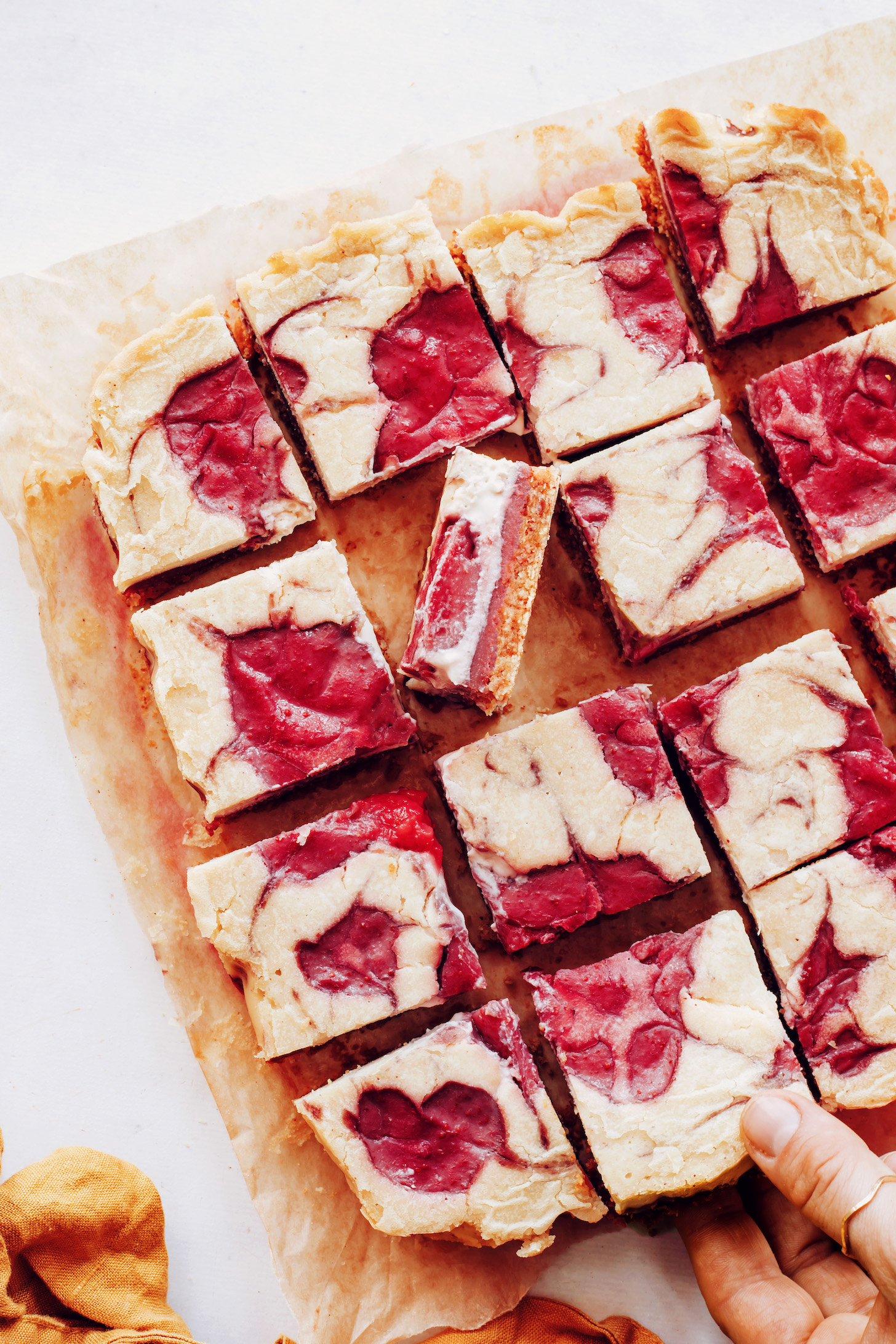 Gluten-free vegan strawberry cheesecake bars on a piece of parchment paper